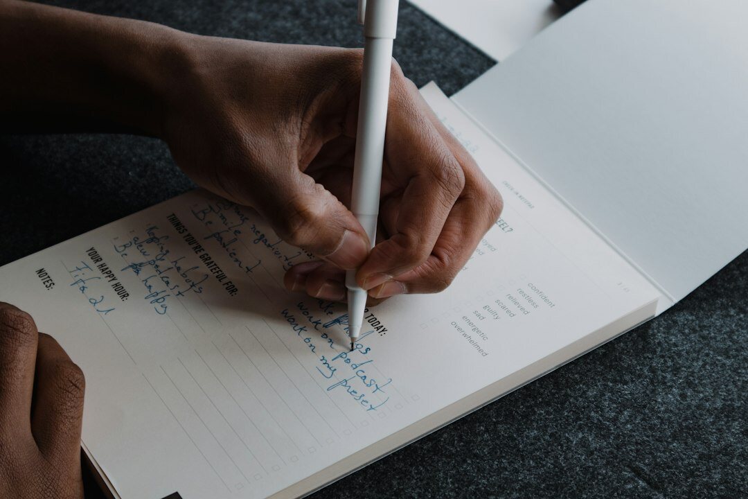 person writing notes in journal